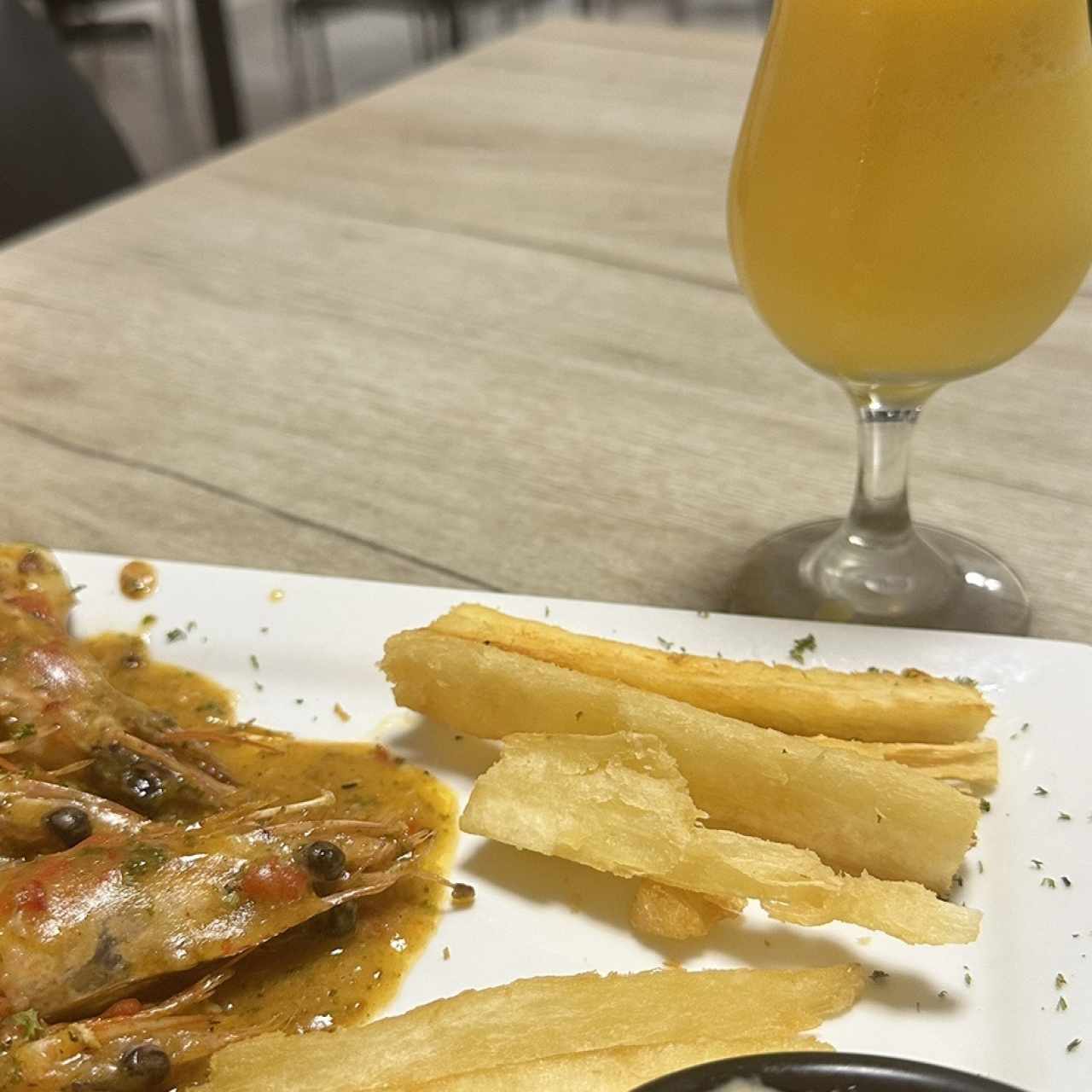 Langostinos al ajillo con yuca frita y jugo de maracuyá en agua. 