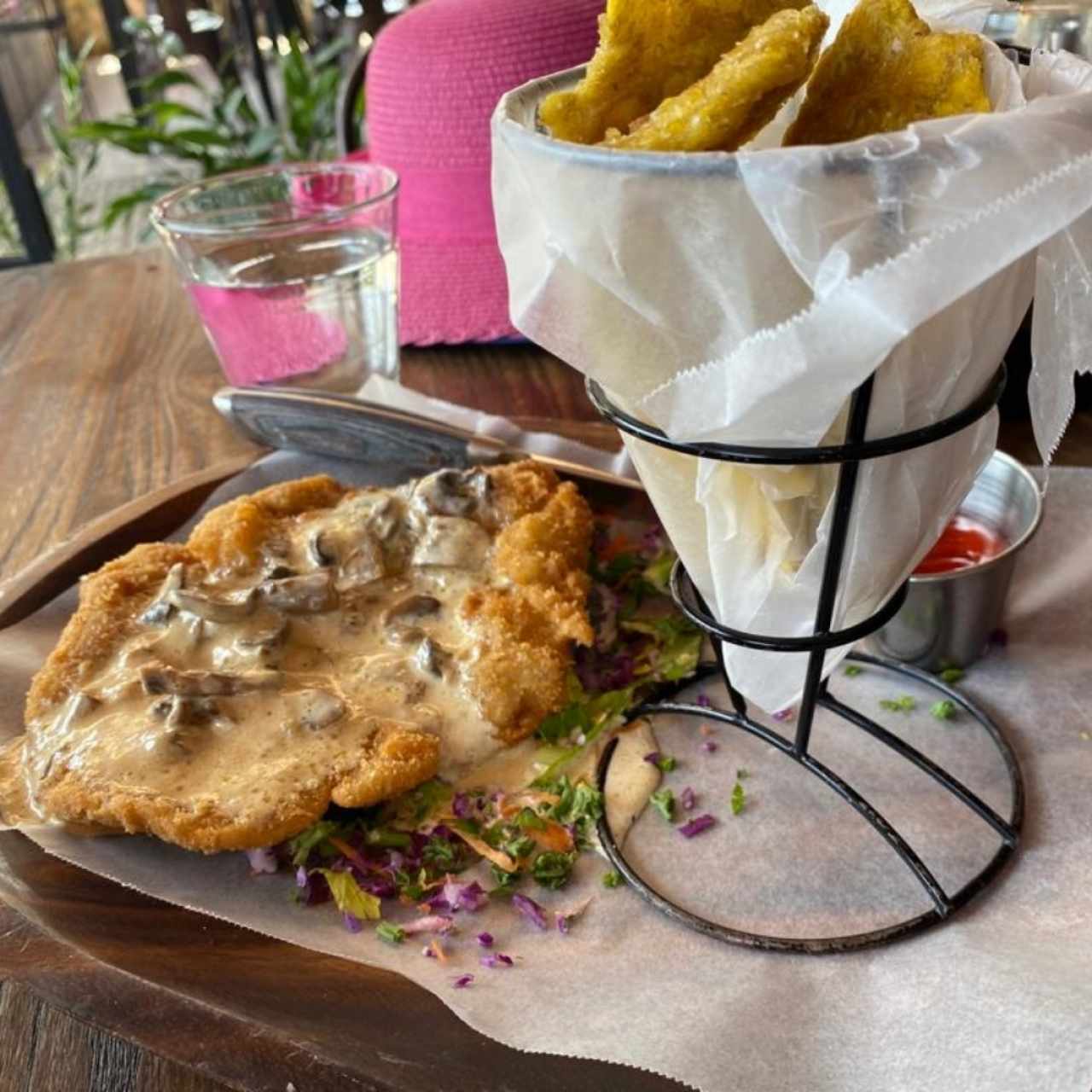 Schnitzel (milanesa) de pollo con salsa de hongos, acompañada de patacones. 