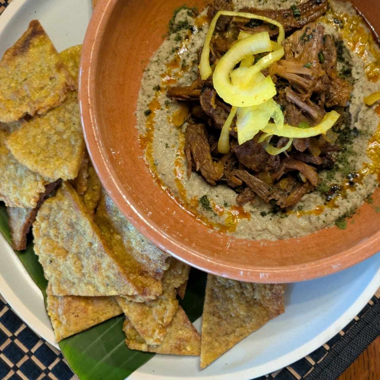 hummus de guandú con brisket y chips de plátano