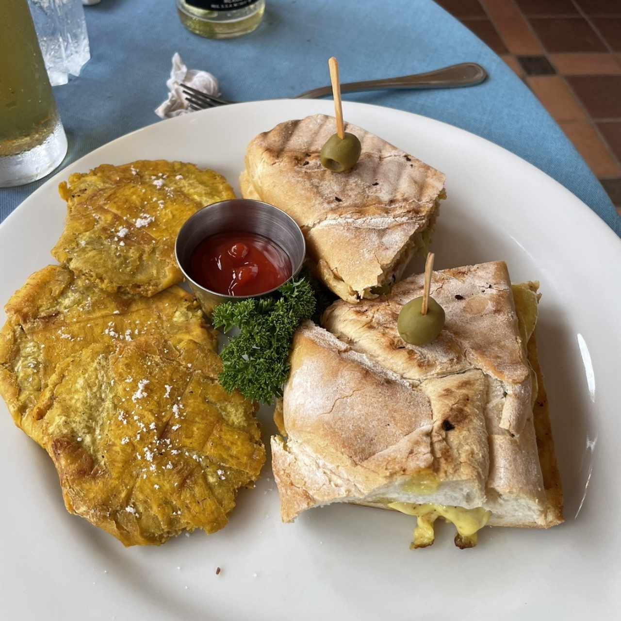 Sandwich Cubano: Pernil, Jamón, queso suizo y pepinillo con tostones de plátano, pan francés