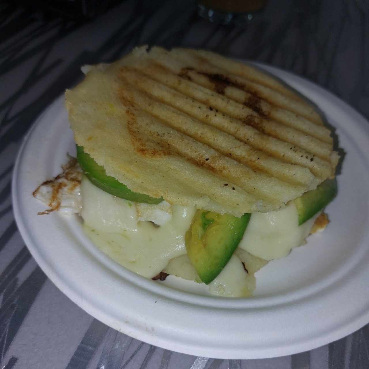 Arepa asada con huevo frito, queso y aguacate