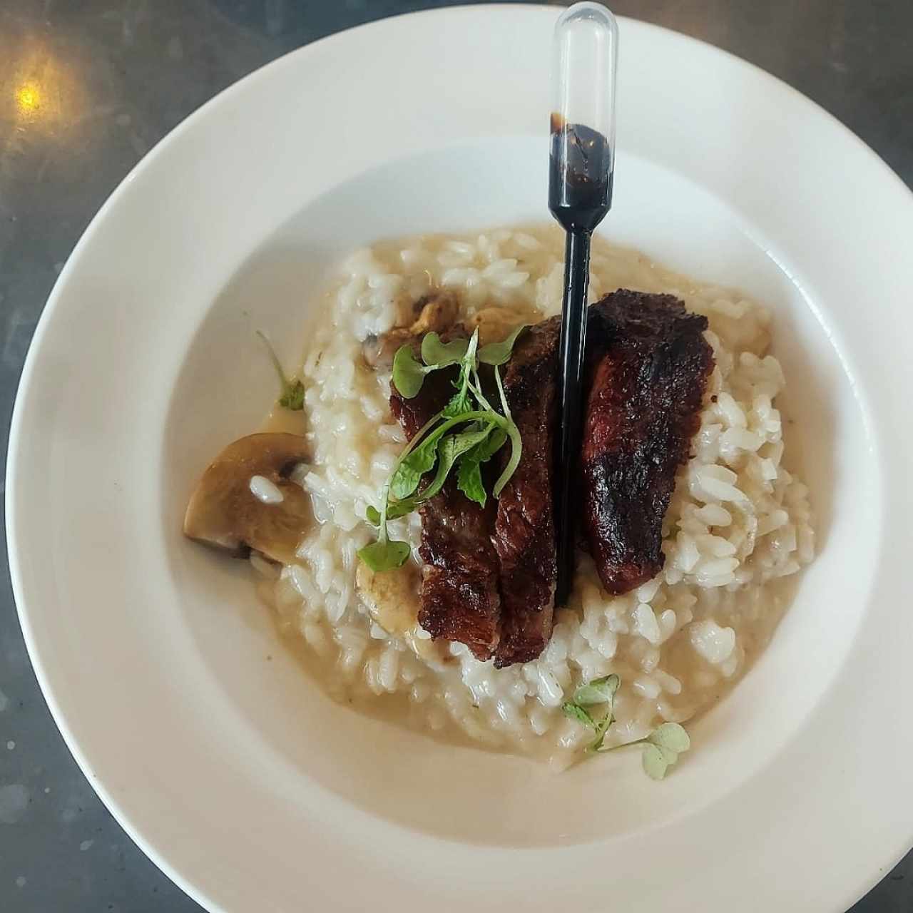 Picaña al grill sobre risotto de hongos y pipeta de balsámico trufado