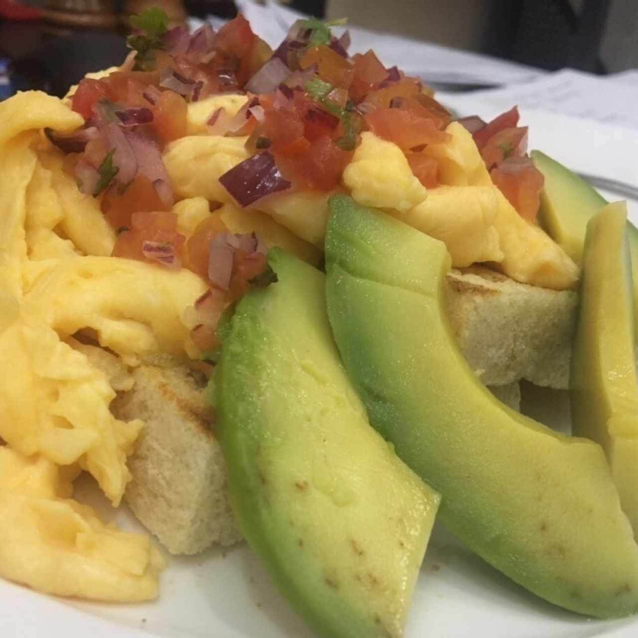 Huevos revueltos, agacate y salsa cruda sobre tostadas