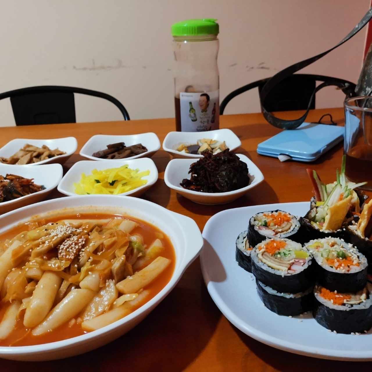 Kimbap y Ttokbokki con entradas variadas y té frío. 