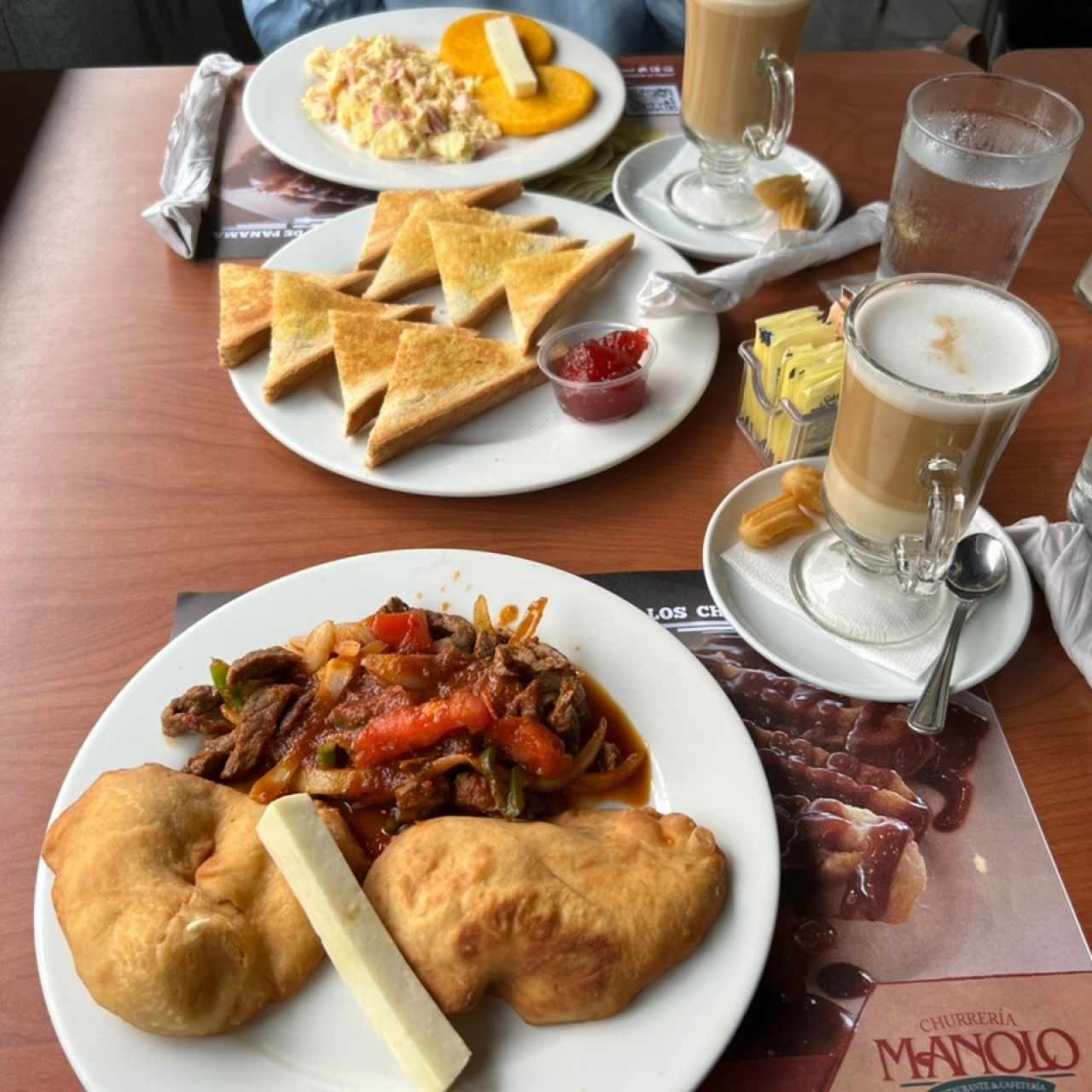 Bistec picado con hojaldras, tostadas con mermelada, huevos revueltos con tortillas y capuccinos