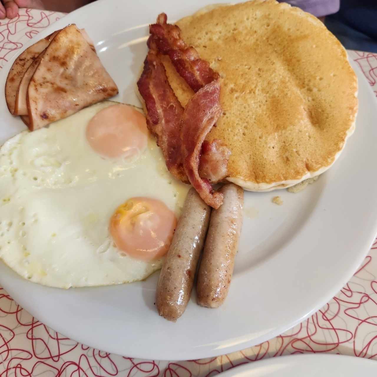 RD's Big Poppa, en la foto faltan las papas ralladas que es muy buena porción y la tostada de pan que tiene buen tamaño, en el plato se ve los 3 pancakes, 2 huevos, 2 tocinos, 2 salchichas y el pavo ahumado.