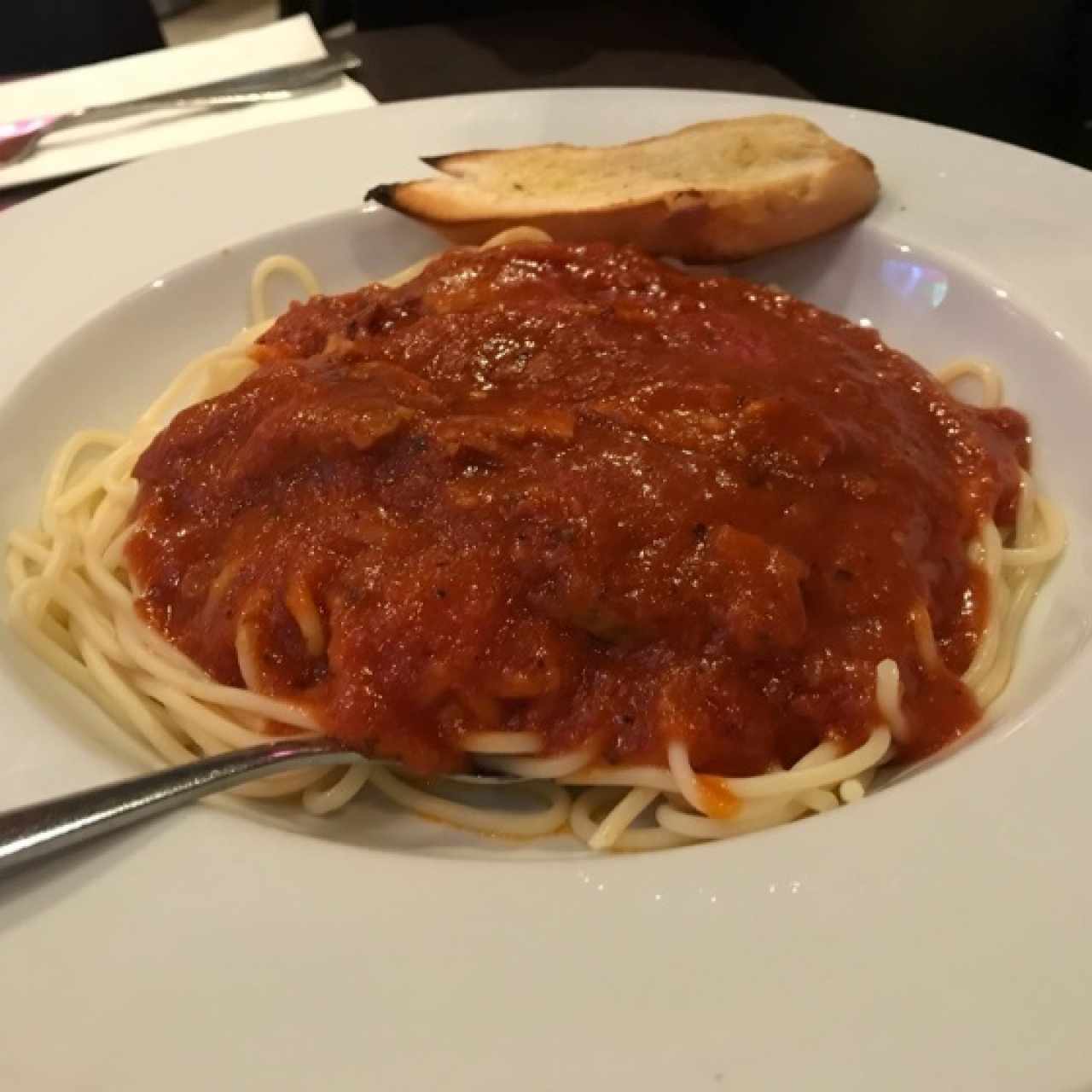 Spaghetti con lomo en salsa roja acompañado de pan de ajo