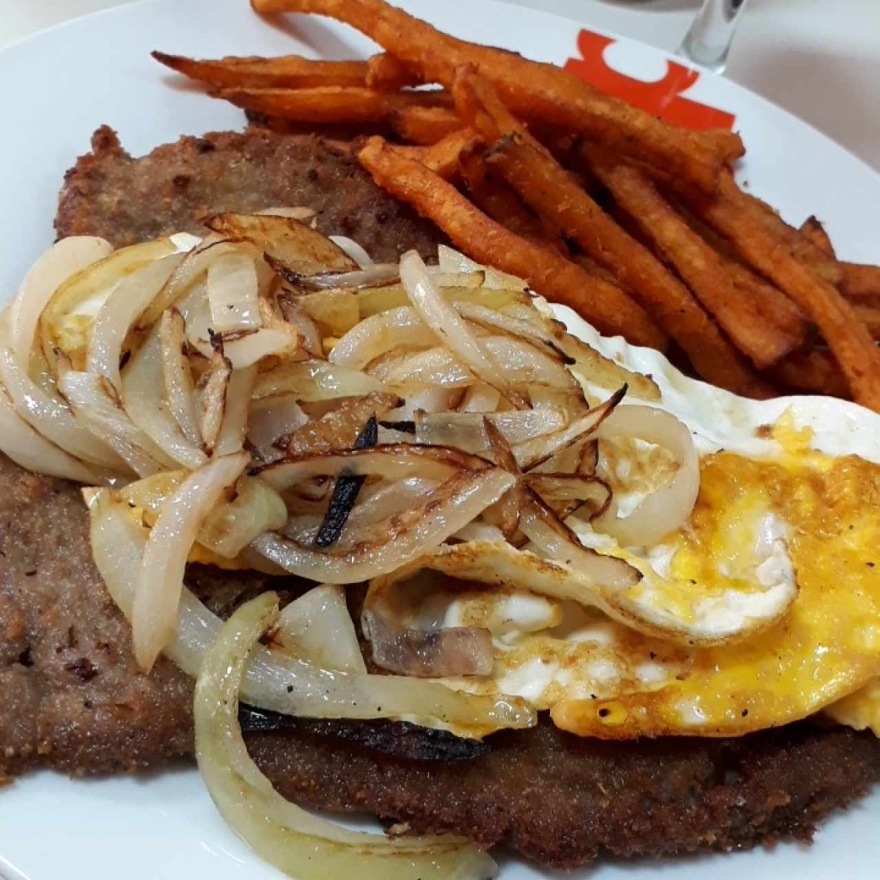 Milanesa con cebolla frita y huevo