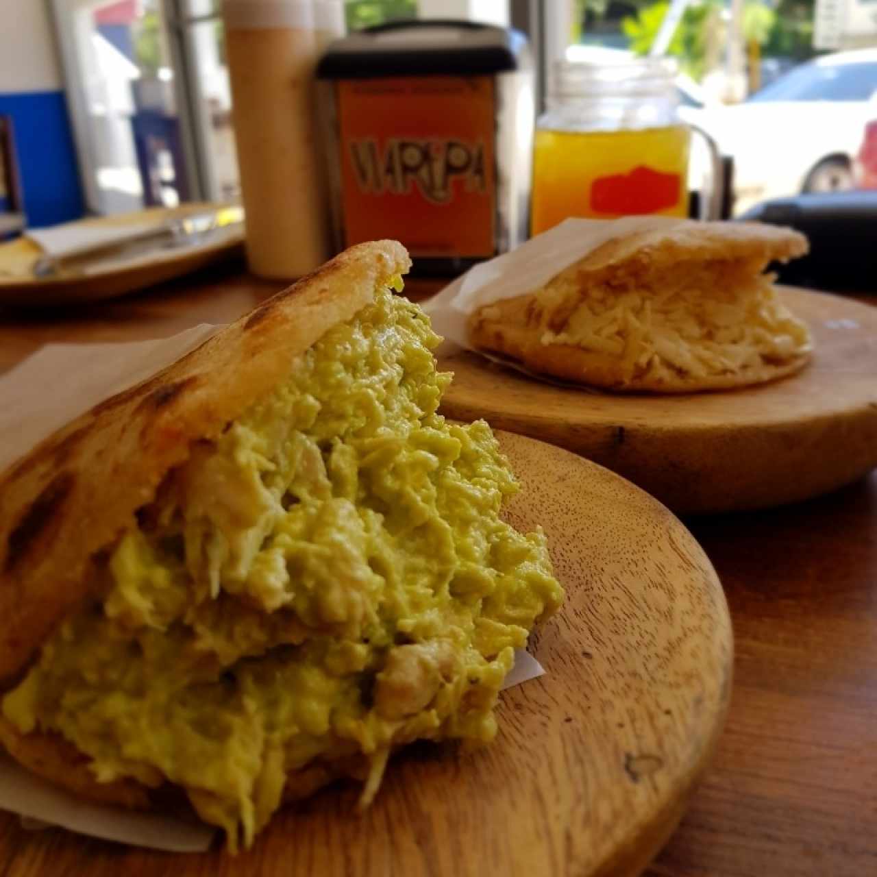 Arepa de Chicharron rellena de Reina Pepiada (primer plano)... Arepa de Chicharron rellena de  queso blanco rayado (segundo plano)