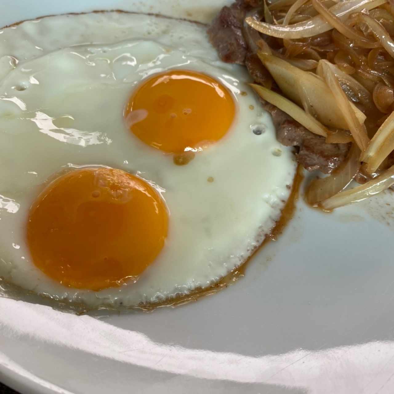 Bistec encebollado con huevos fritos