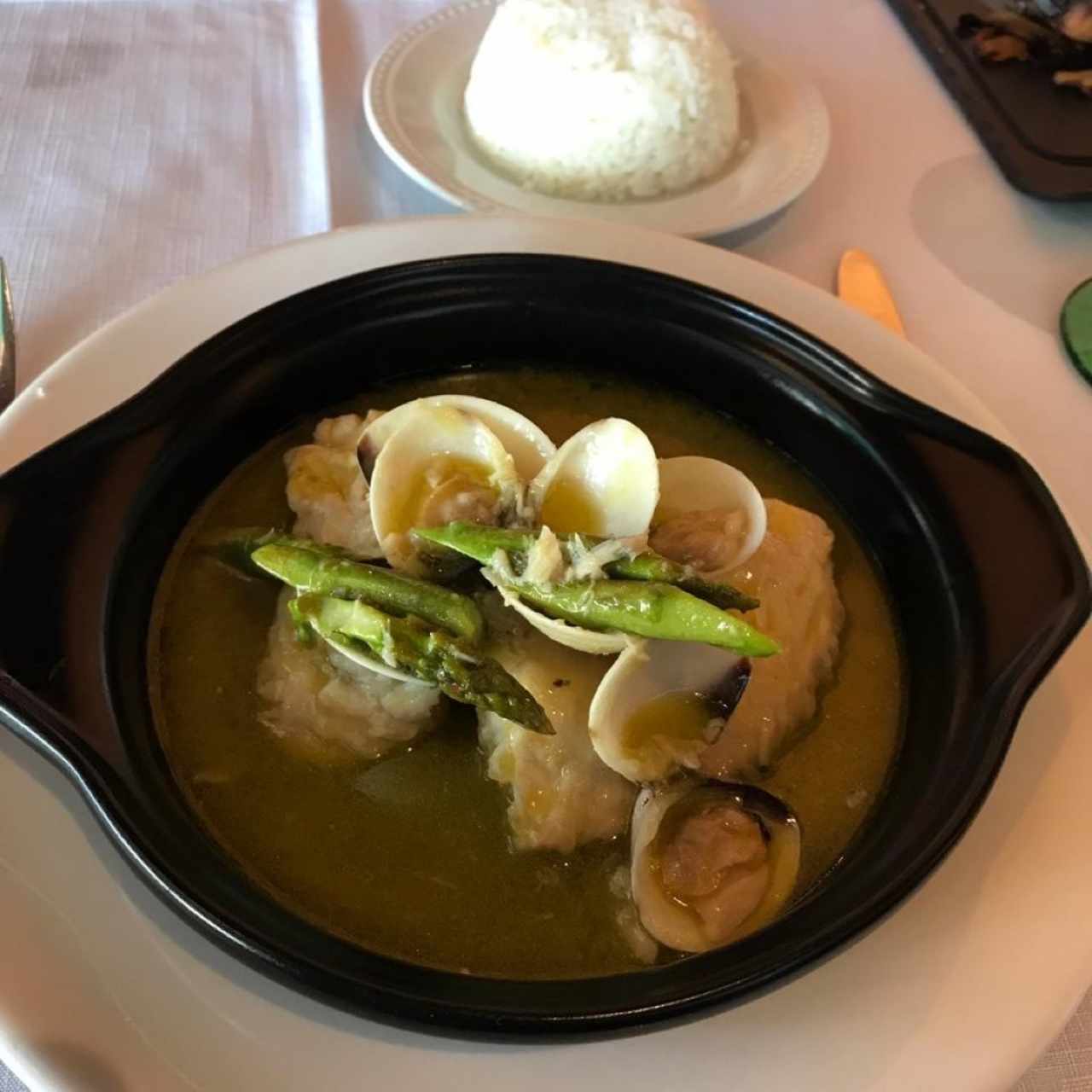 Corvina con almejas y espárragos en salsa verde.