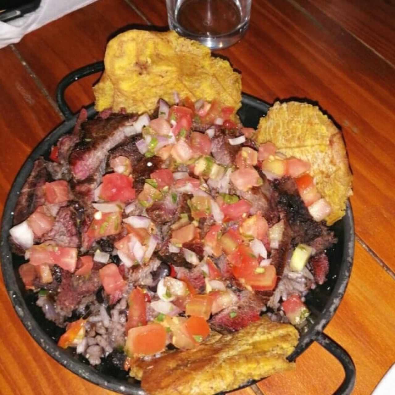 Carne ahumada con patacones, pico de gallo y arroz con frijoles negros.