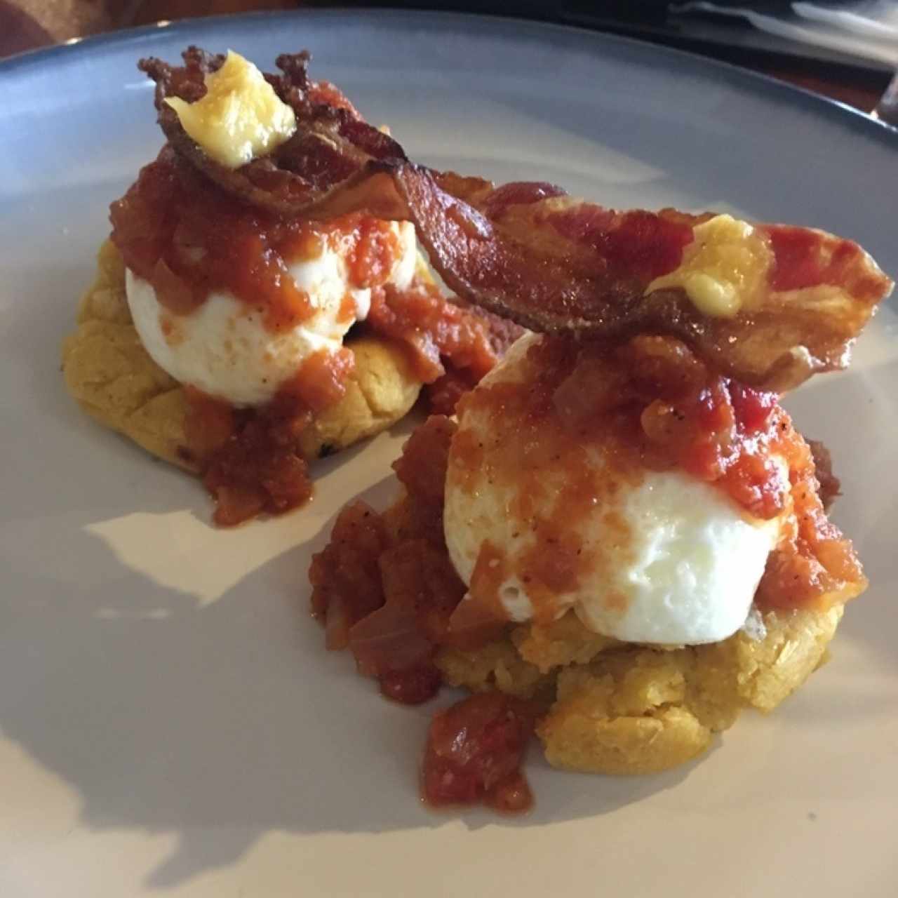 huevos pochados sobre changa de maíz casera, con bacon y salsa especial