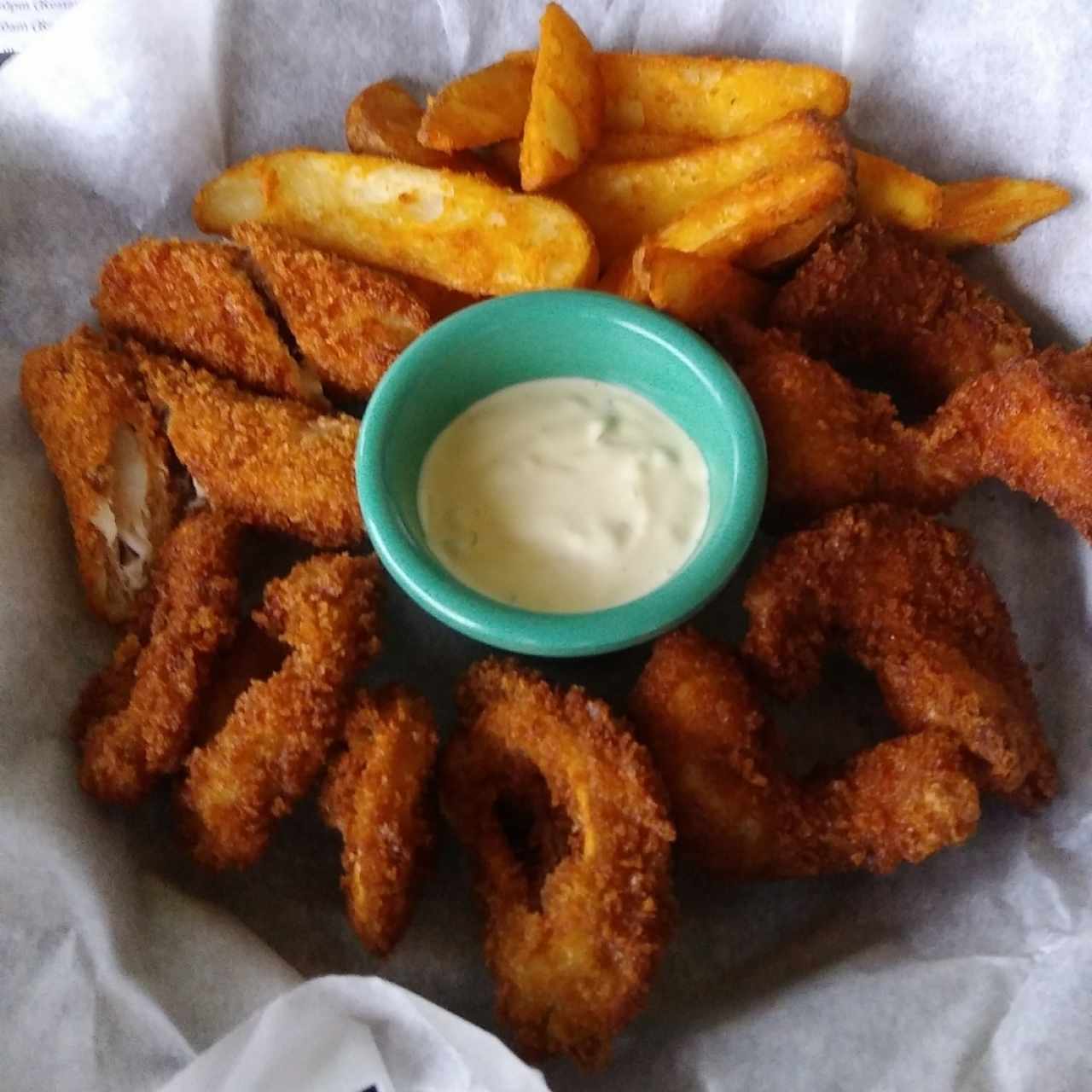 Dedos de pescado, aros de calamar y camarones apanados, con papas wedge.