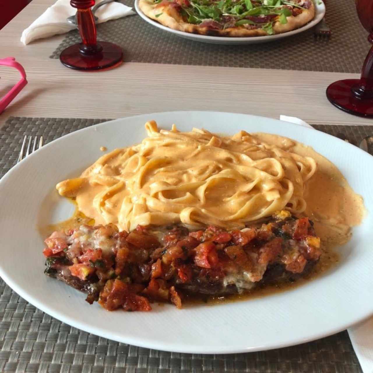 Carne gratinada con tomate y queso acompañada de pasta en salsa rosada