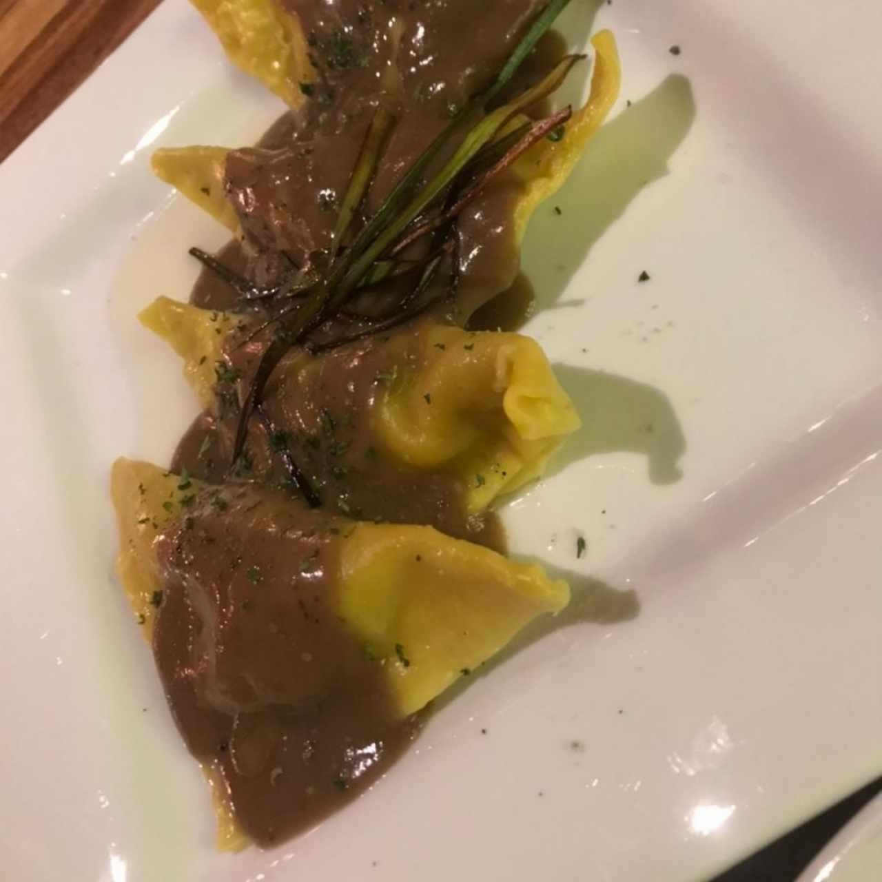 Raviolis de pasta wonton rellenos de camarón y corvina con salsa de hongos y aceite de trufa