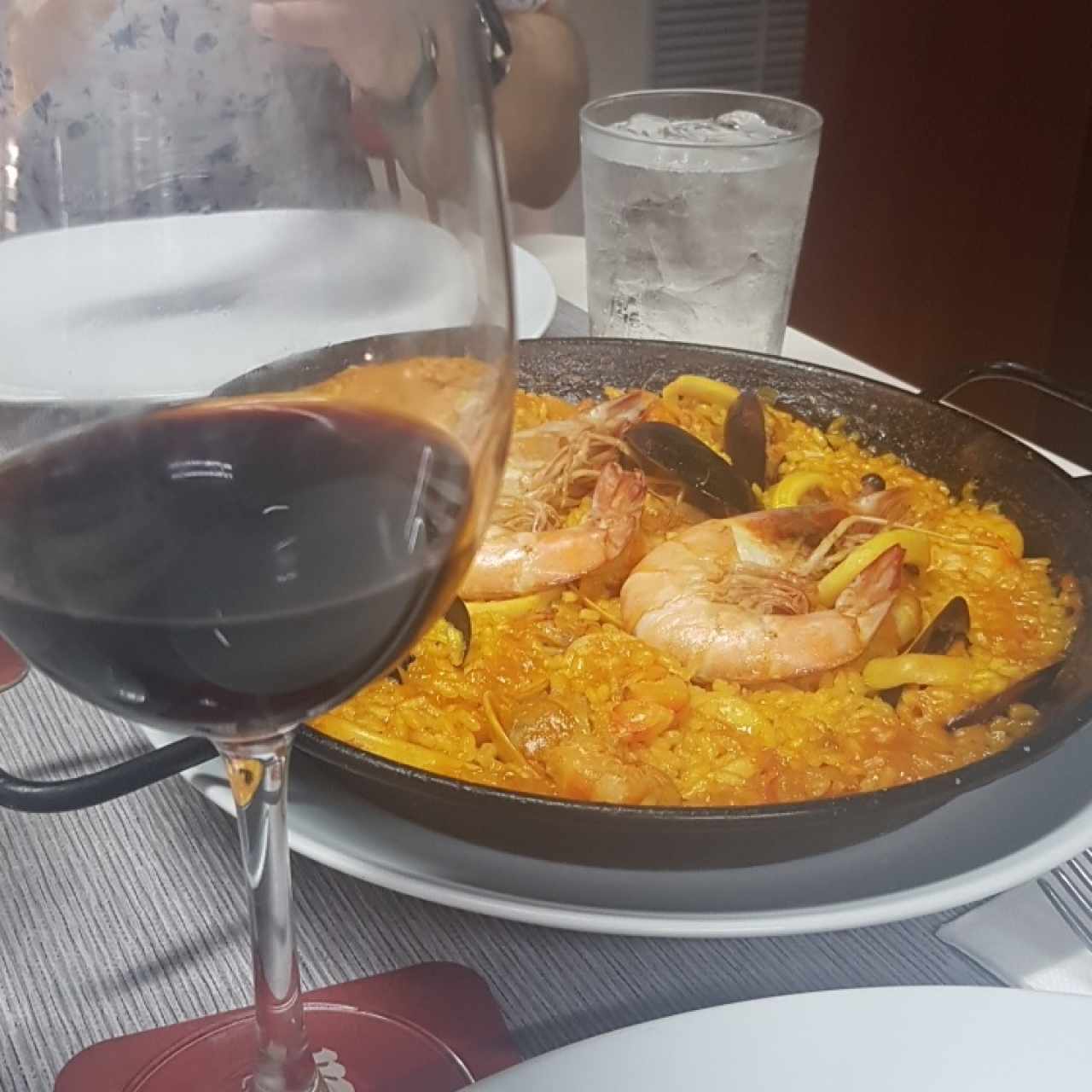 paella de mariscos con una copa de vino tinto 