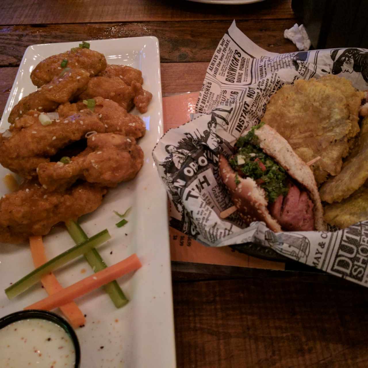 Alitas con salsa Buffalo y Choripan (sólo aparece la mitad) con patacones 