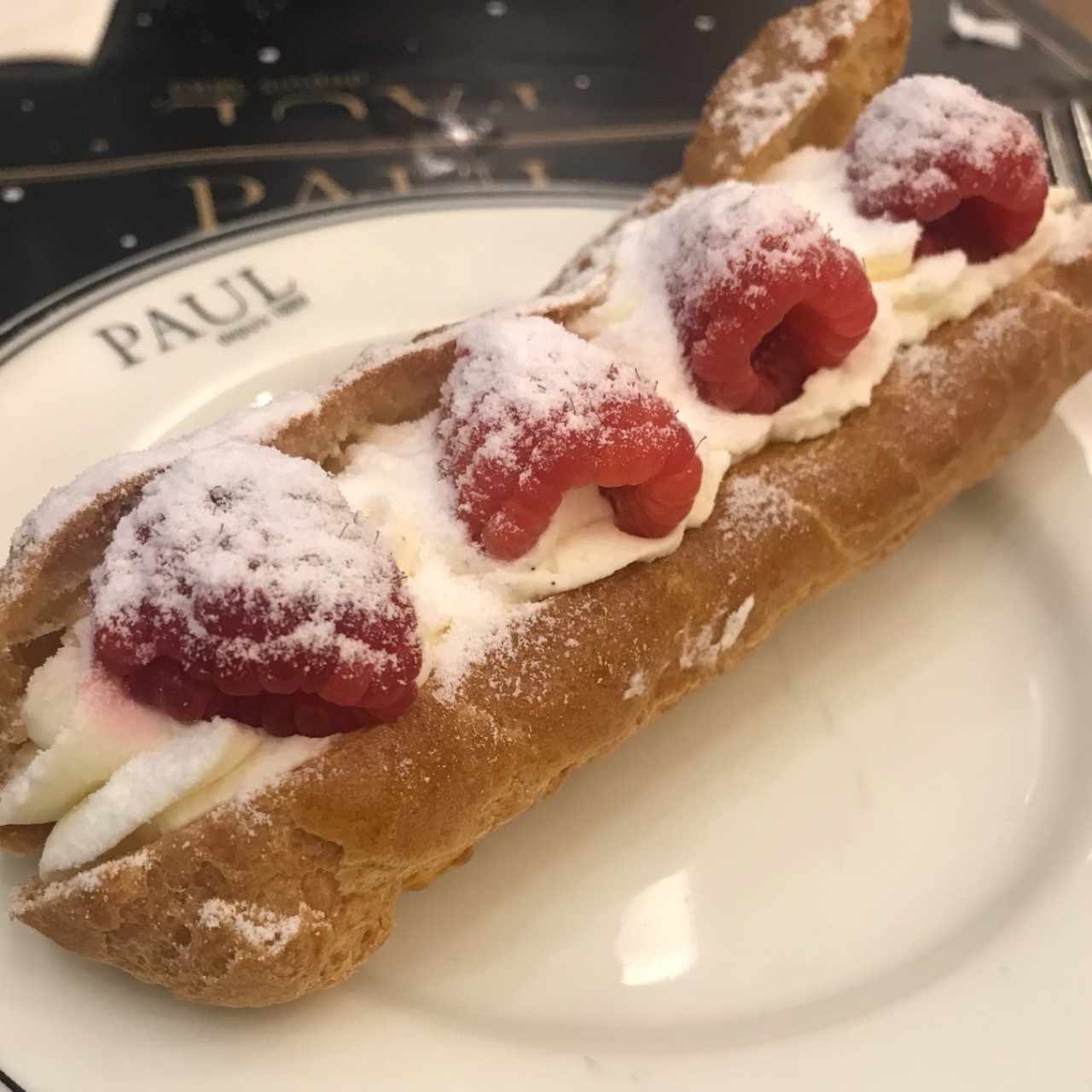 Eclair relleno con crema y frambuesas 