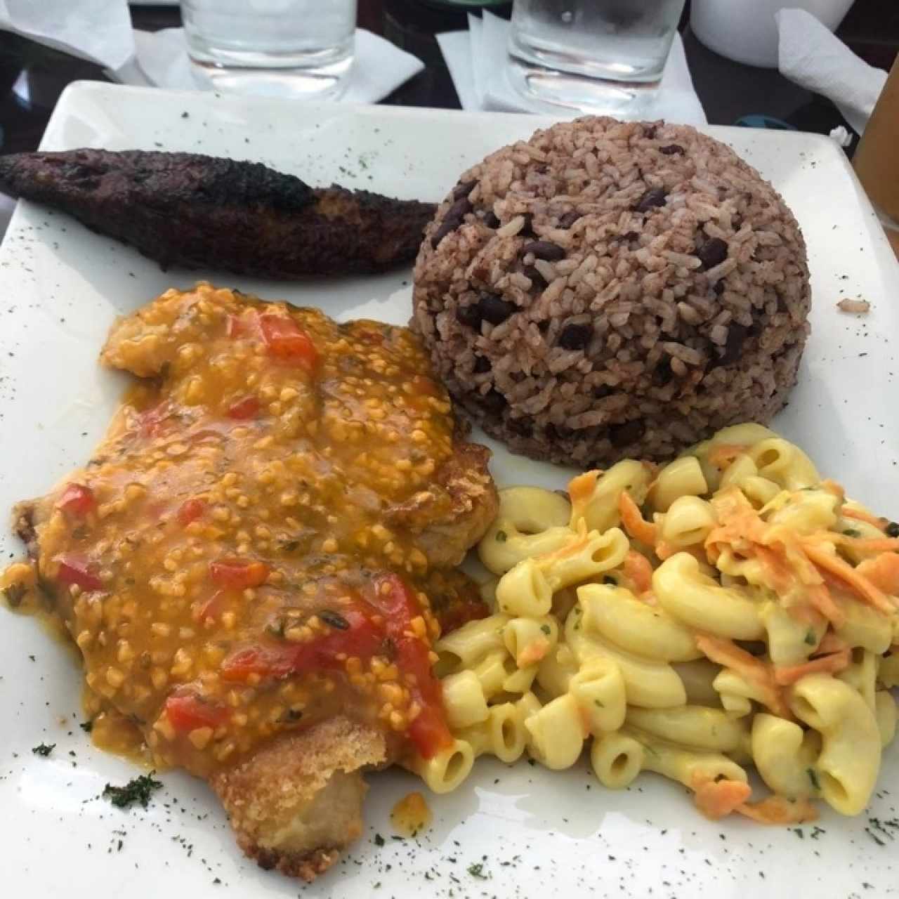 Filete de pescado con salsa a la criolla con arroz con coco, plátano y ensalada