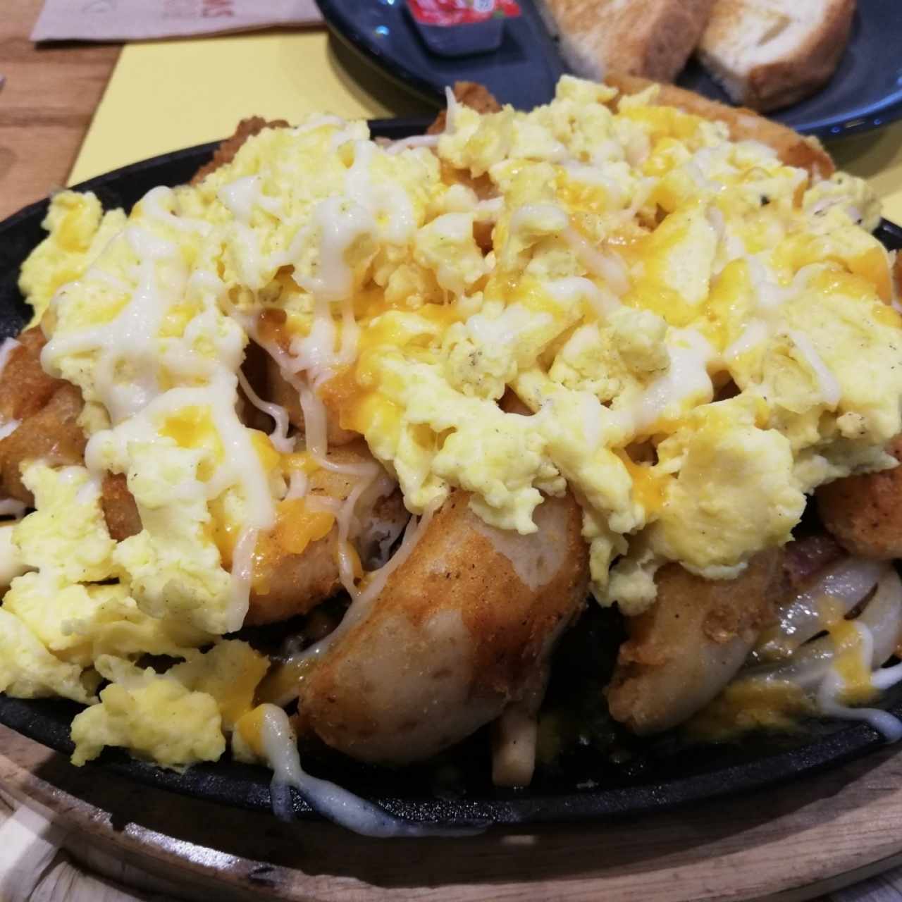 huevos revueltos con hongos, cebollas, balcón, pimentónes, salchichas y queso sobre papas en lascas