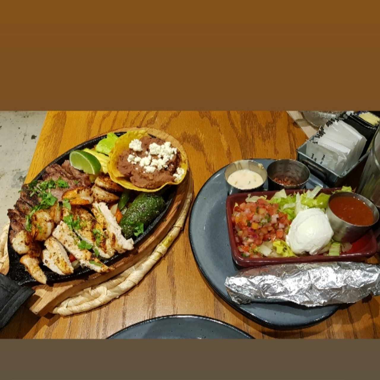 Fajitas mixtas (carne, pollo y camarones) a un lado, pico de gallo, sour cream etc