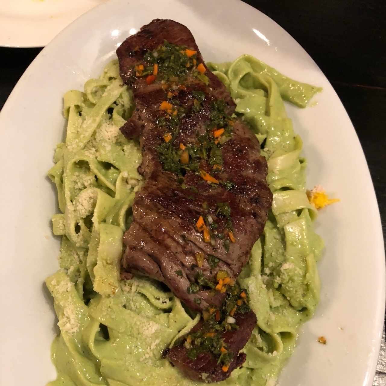 churrasco sobre una cama de tallarines al pesto 