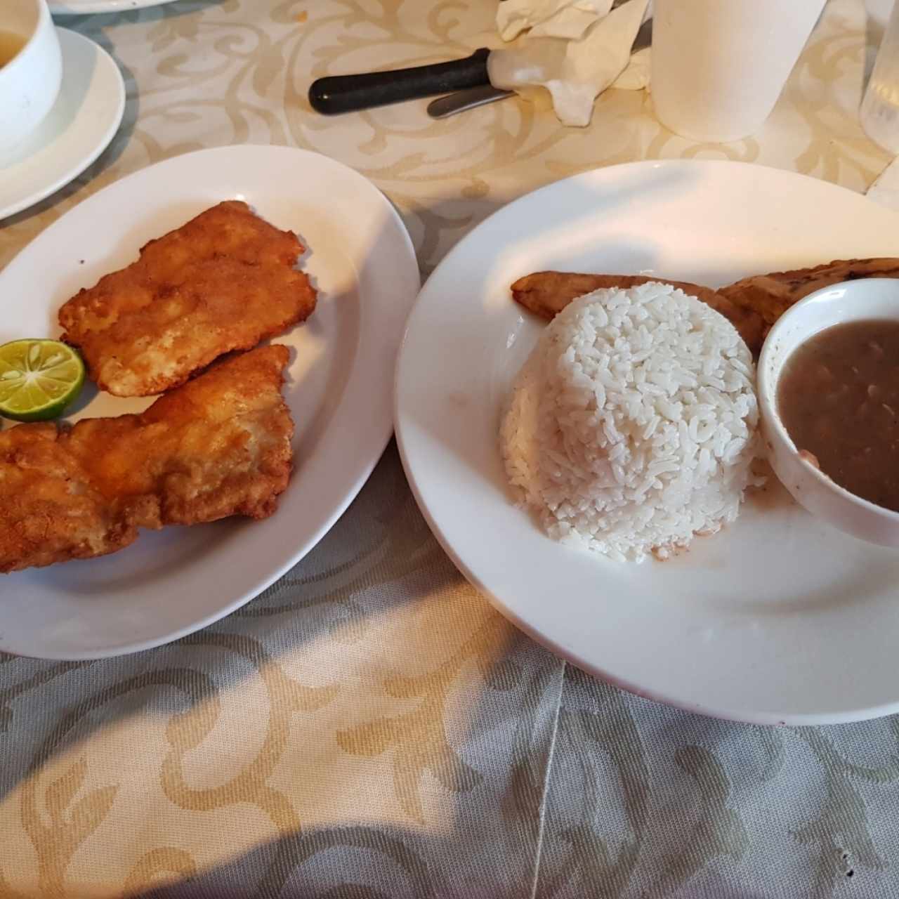 Filete de corvina apanado con arroz, porotos y tajadas.