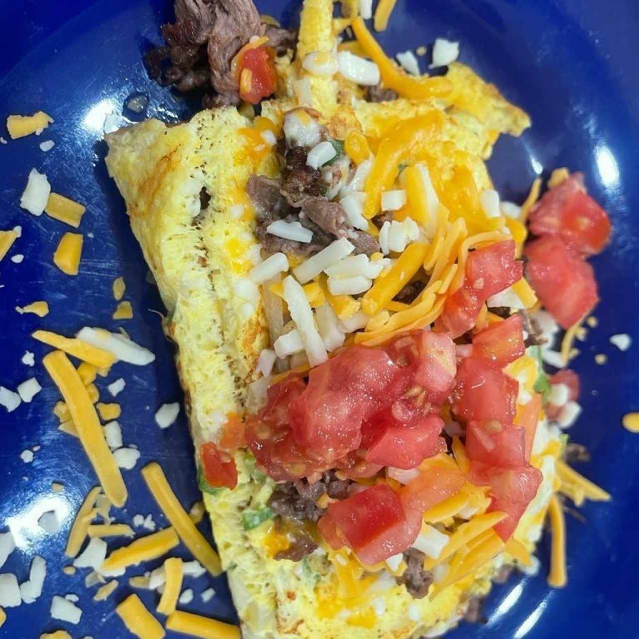 BIG STEAK OMELETTE (Tiernas tiras de bistec, papa hash browns, pimiento verde fresco, cebolla, champiñones, tomate y queso Cheddar - Porción Ligera)