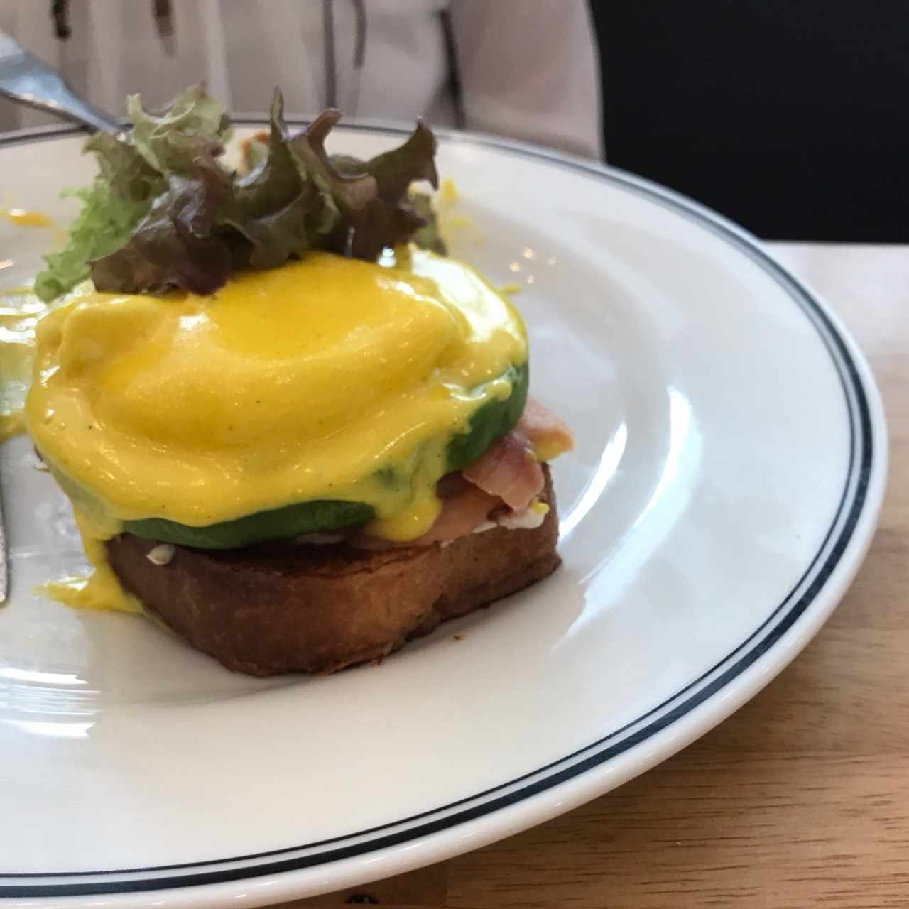 huevos pochados en una cama de salmon ahumado queso crema con aguacate y salsa