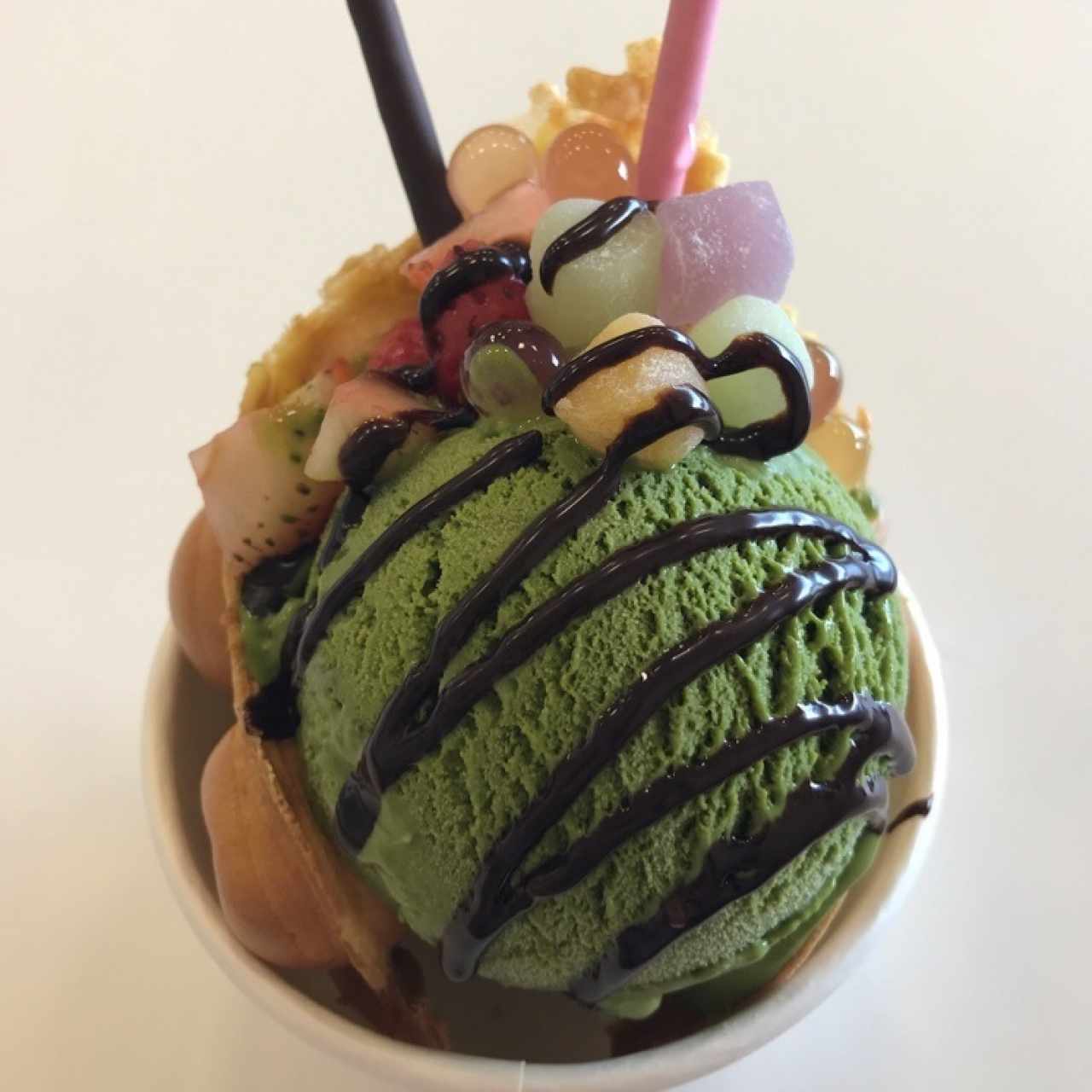 Bubble waffle original con helado de matcha con mochi, fresas y popping bobba como topping.