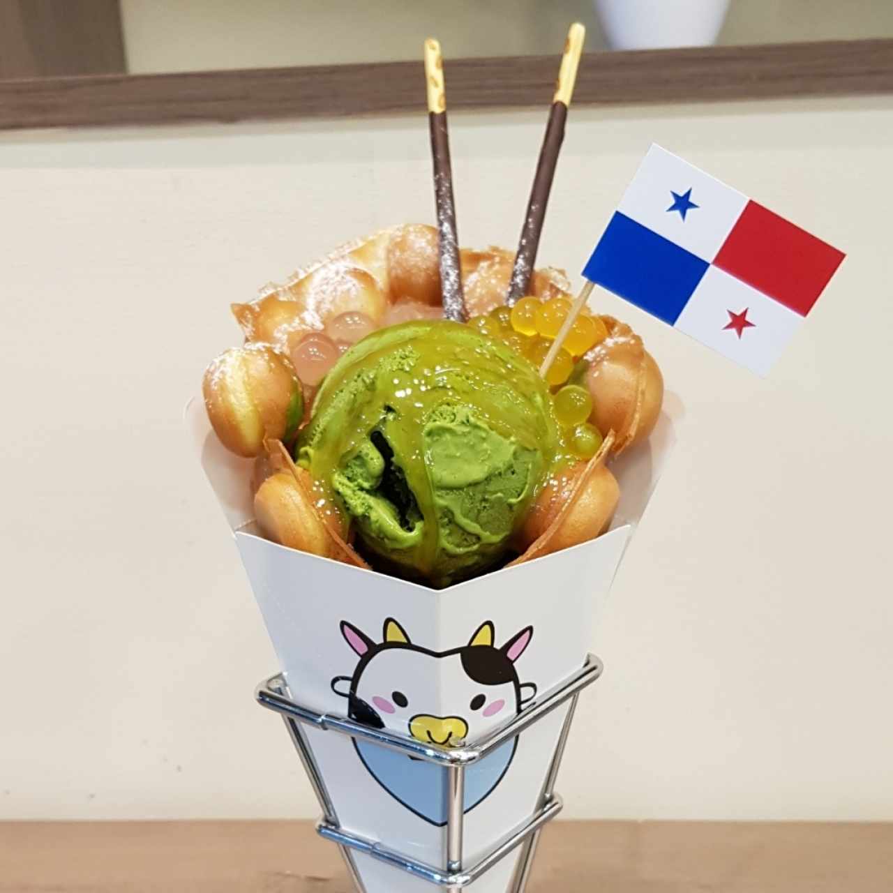 Egg waffle gelato, helado de matcha, popping bubble de rosa y mango, topping de caramelo y pepero de chocolate