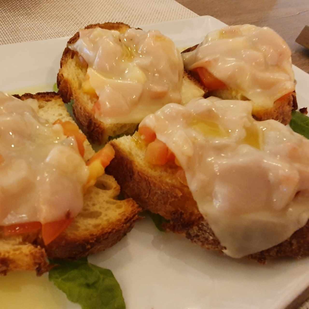 Pan de la casa con trozos de tomate y queso gratinado.