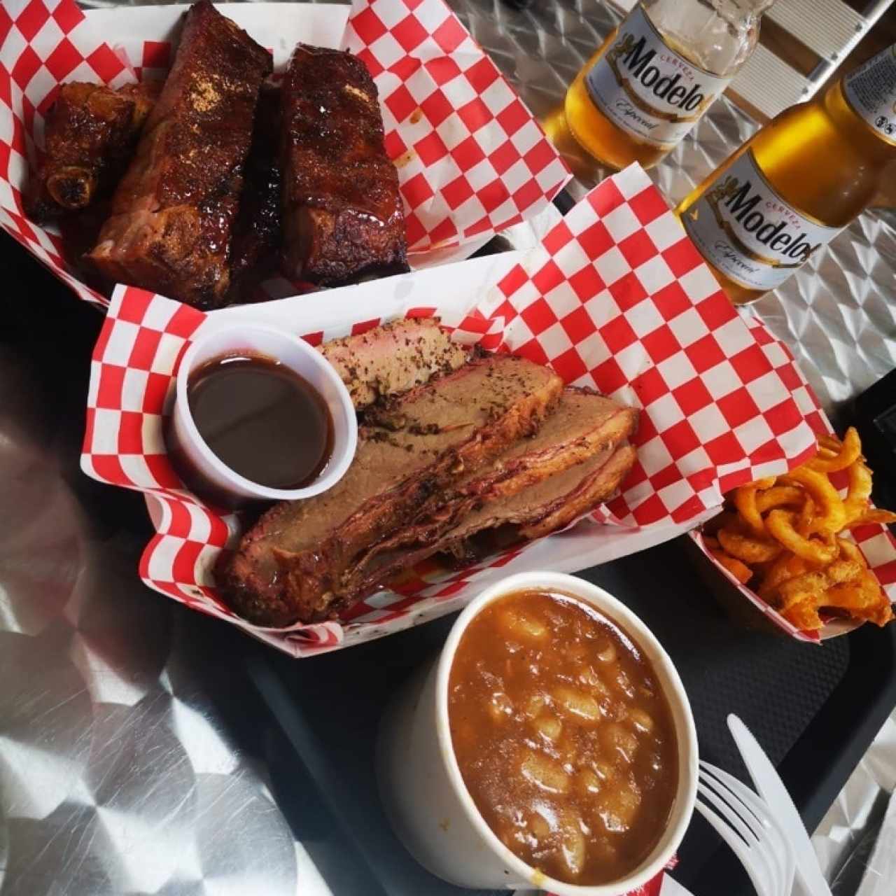 costillas y brisket acompañados de papas fritas y frijoles. 