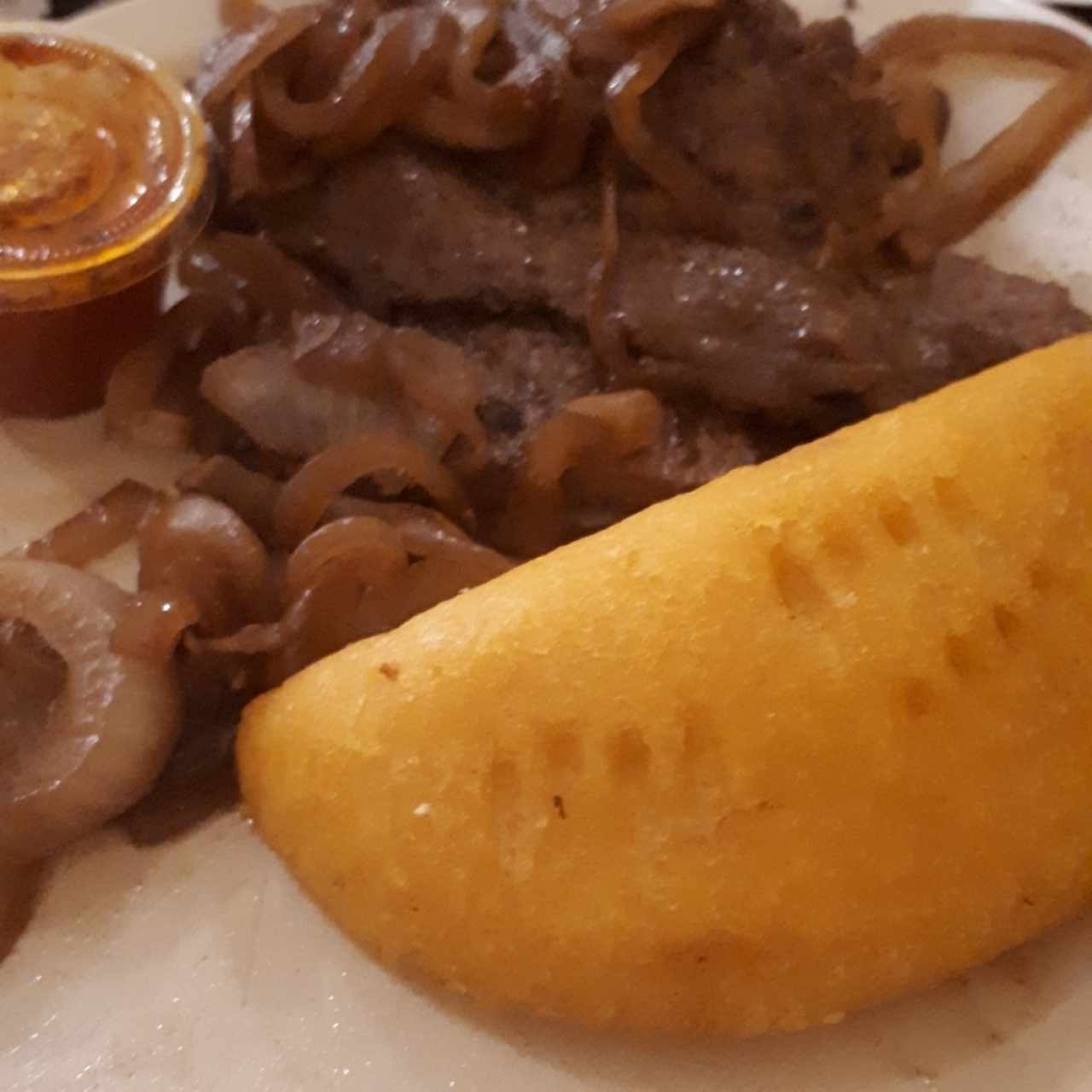 Bistec Encebollado con empanada de maíz 