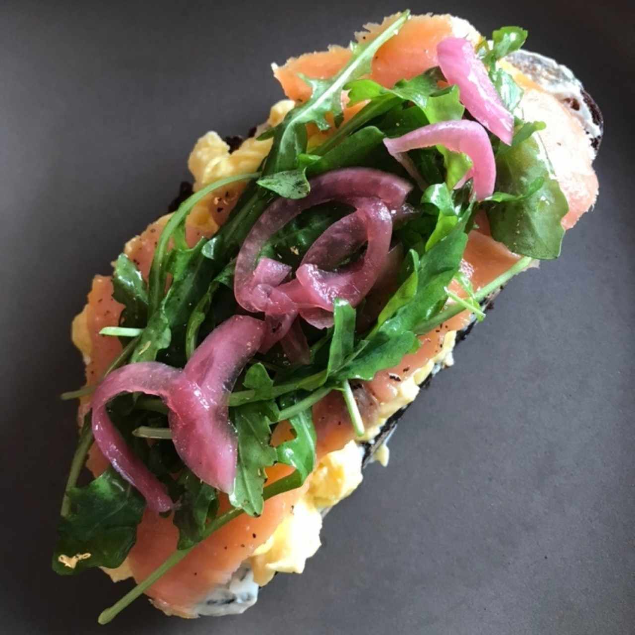 Tostada con huevo, salmon, arugula, cebolla encurtida y otras cosas wenas