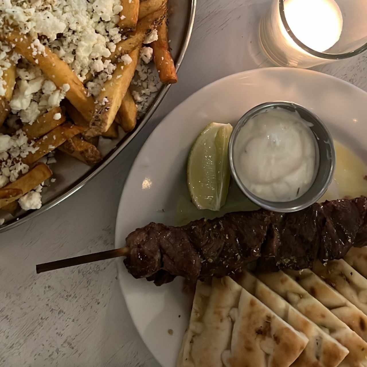 Papas fritas con feta y pincho de cordero 