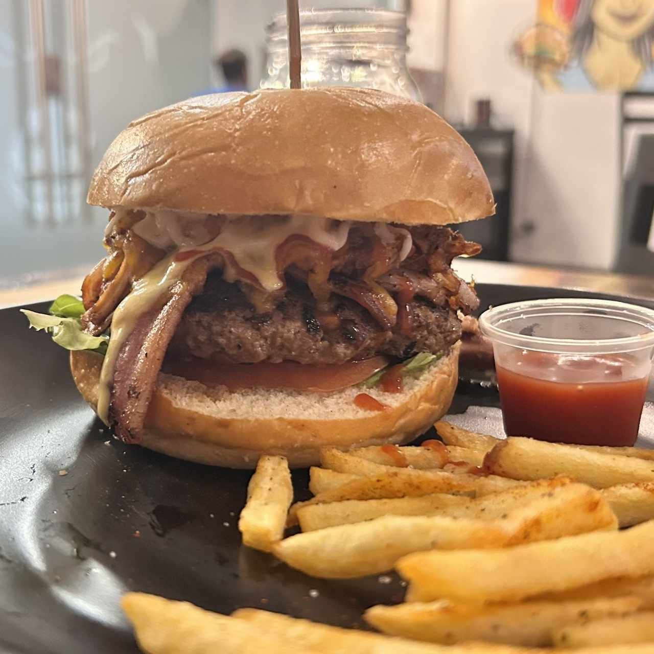 Rockstar Burger Pattie de la casa preparado al carbón, con fresco tomate, lechuga, bañados con queso cheddar rallado, pulled en salsa BBQ, bacon, coronado con salsas tradicionales, salsa samurái de la casa todo esto forrado en pan de mantequilla acompañadas con papas fritas.