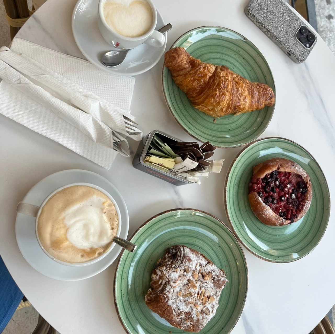 Capuchino, latte, croissant plain, croissant de chocoalmendras y dulce con arándanos