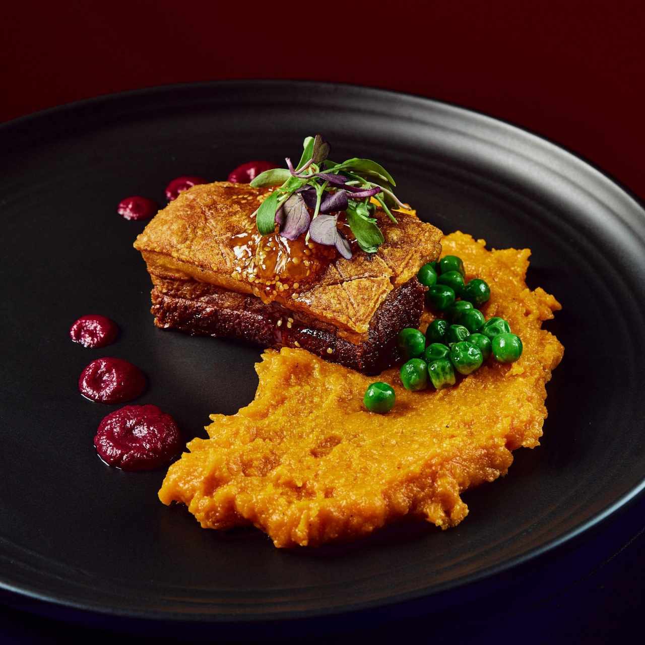 Panceta de cerdo glaseado con miel de caña y mermelada de uchuva sobre un tamal de olla criollo