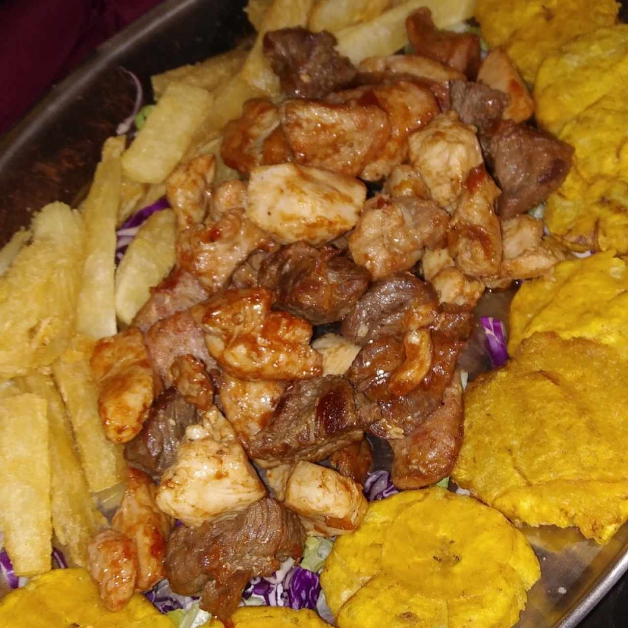 Bandeja de carnes con patacones y yucas fritas.