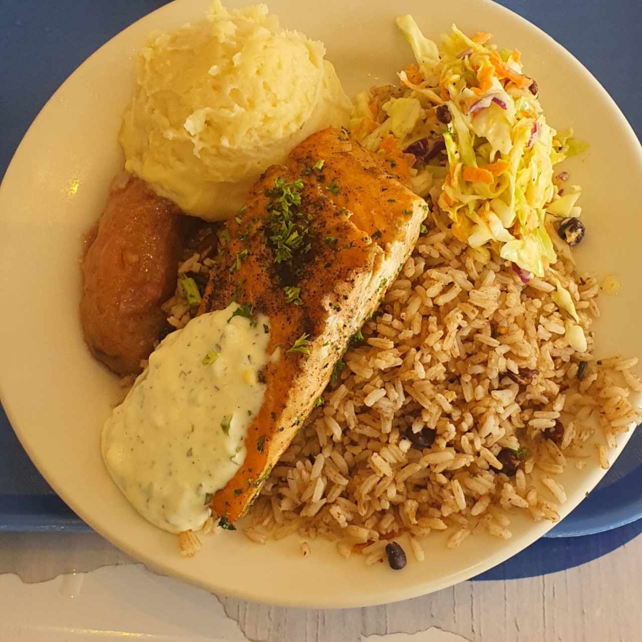 Arroz con frijoles, salmón, ensalada de repollo, puré y plátano en tentación.