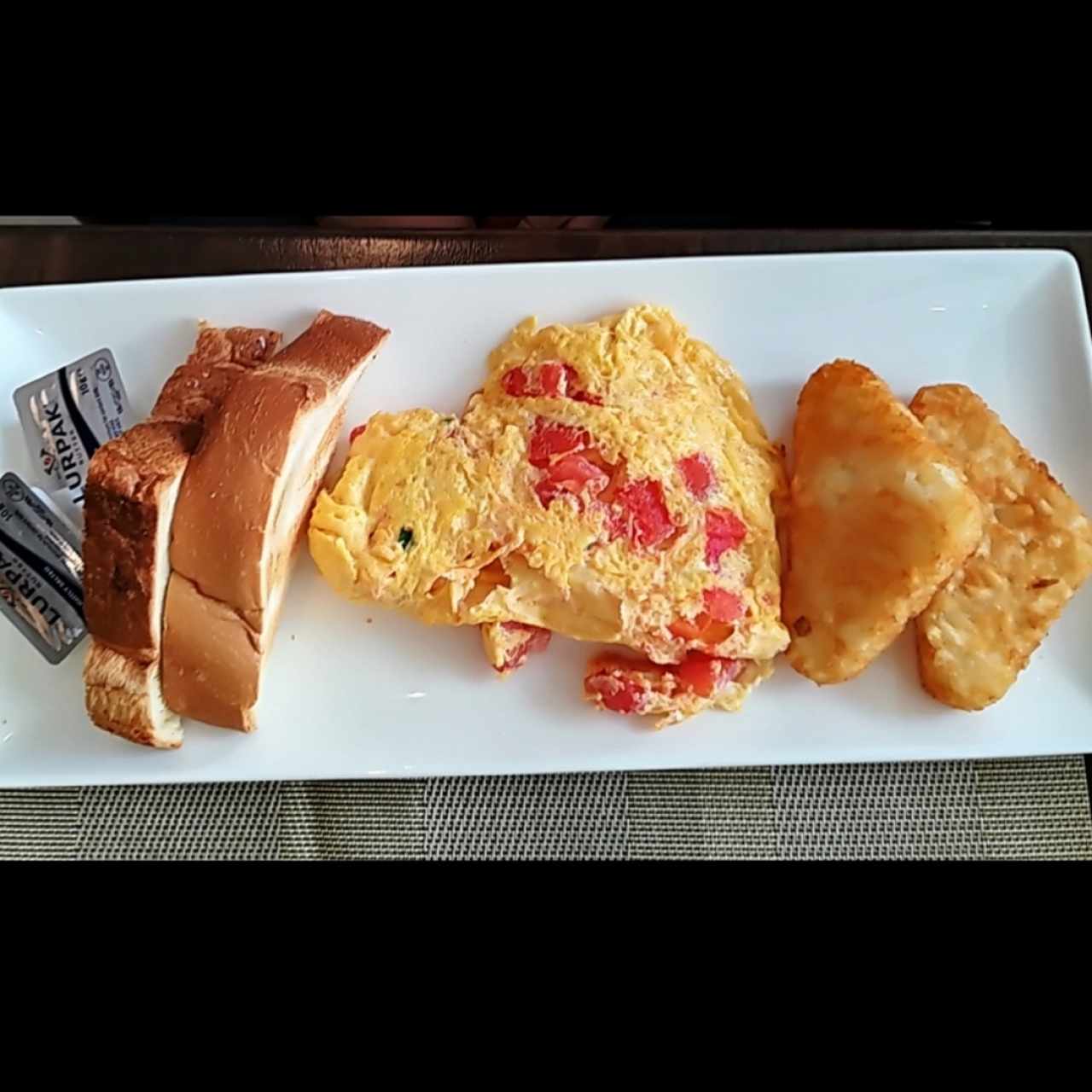 Huevos con tomate, hash browns y tostadas