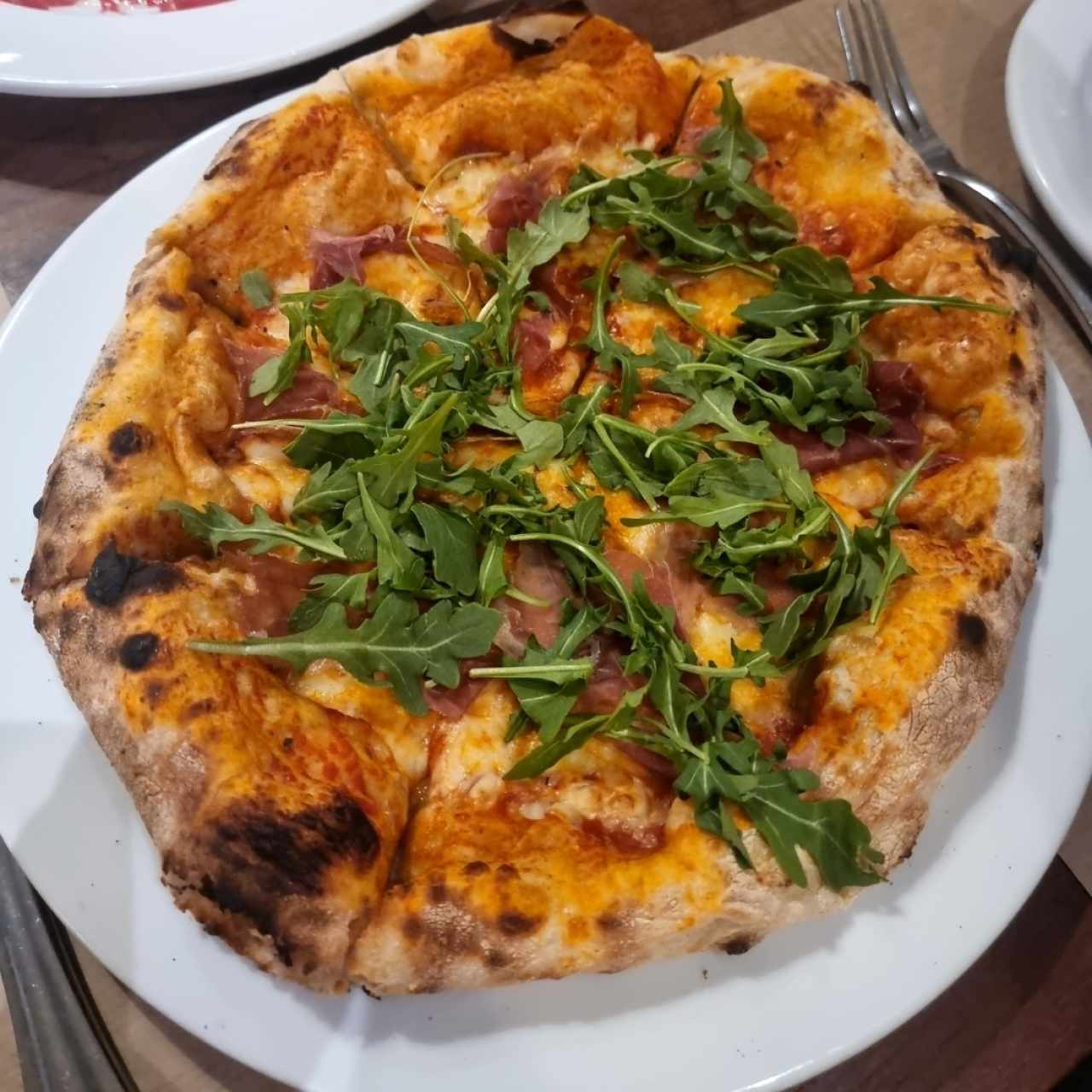 Pizza de proscuitto y arúgula