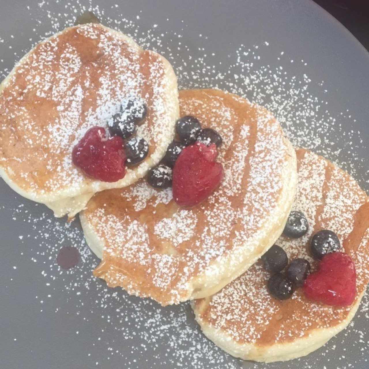 Pancakes con frutilla, miel de maple y azúcar glass 