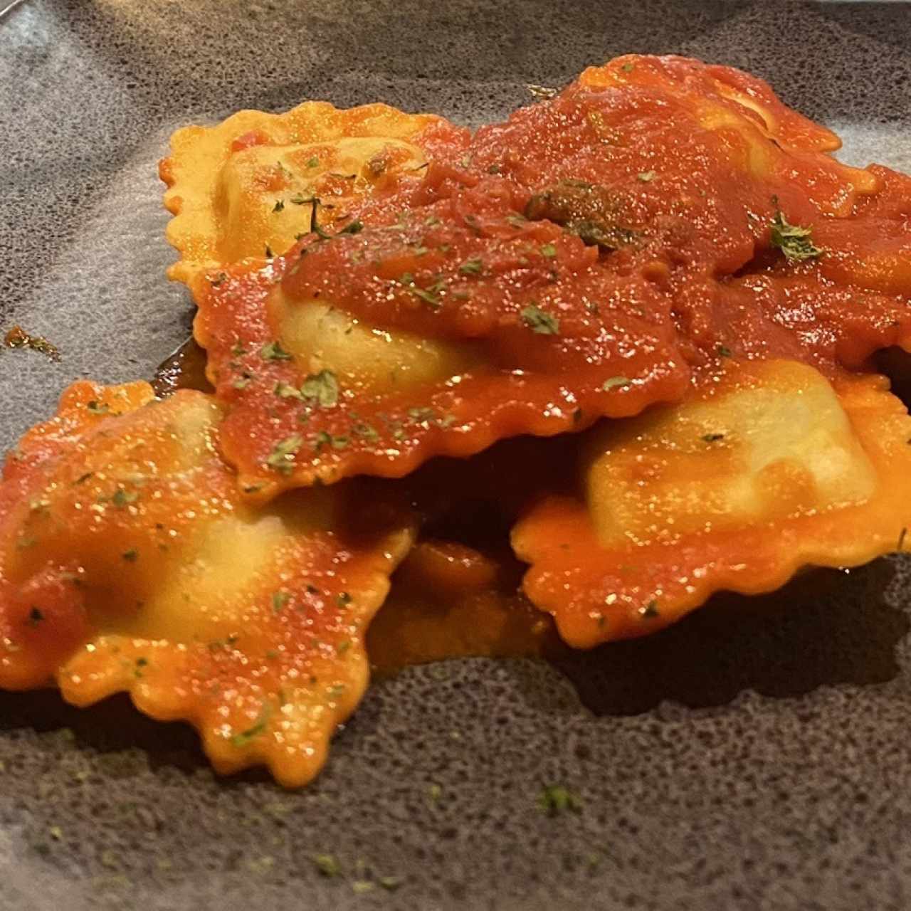 Ravioli de queso y espinaca con salsa roja.