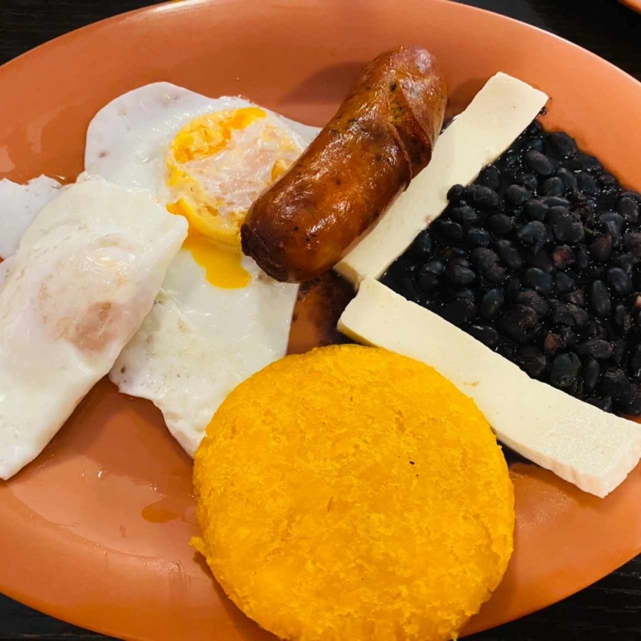 Huevos fritos con chorizo, tortilla y frijoles negros con queso blanco.