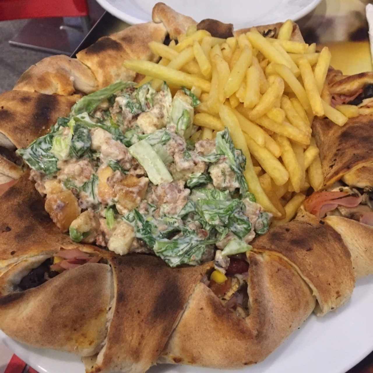 Pizza Volcán con bordes rellenos acompañada de ensalda César y papas fritas